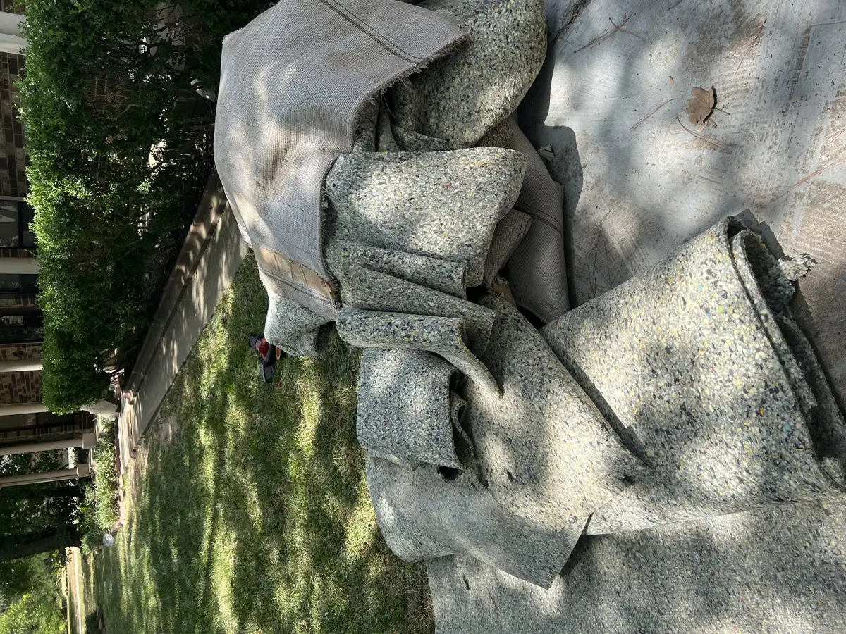 Rolled carpet and padding staged on the driveway for haul-away in Conroe TX 77304